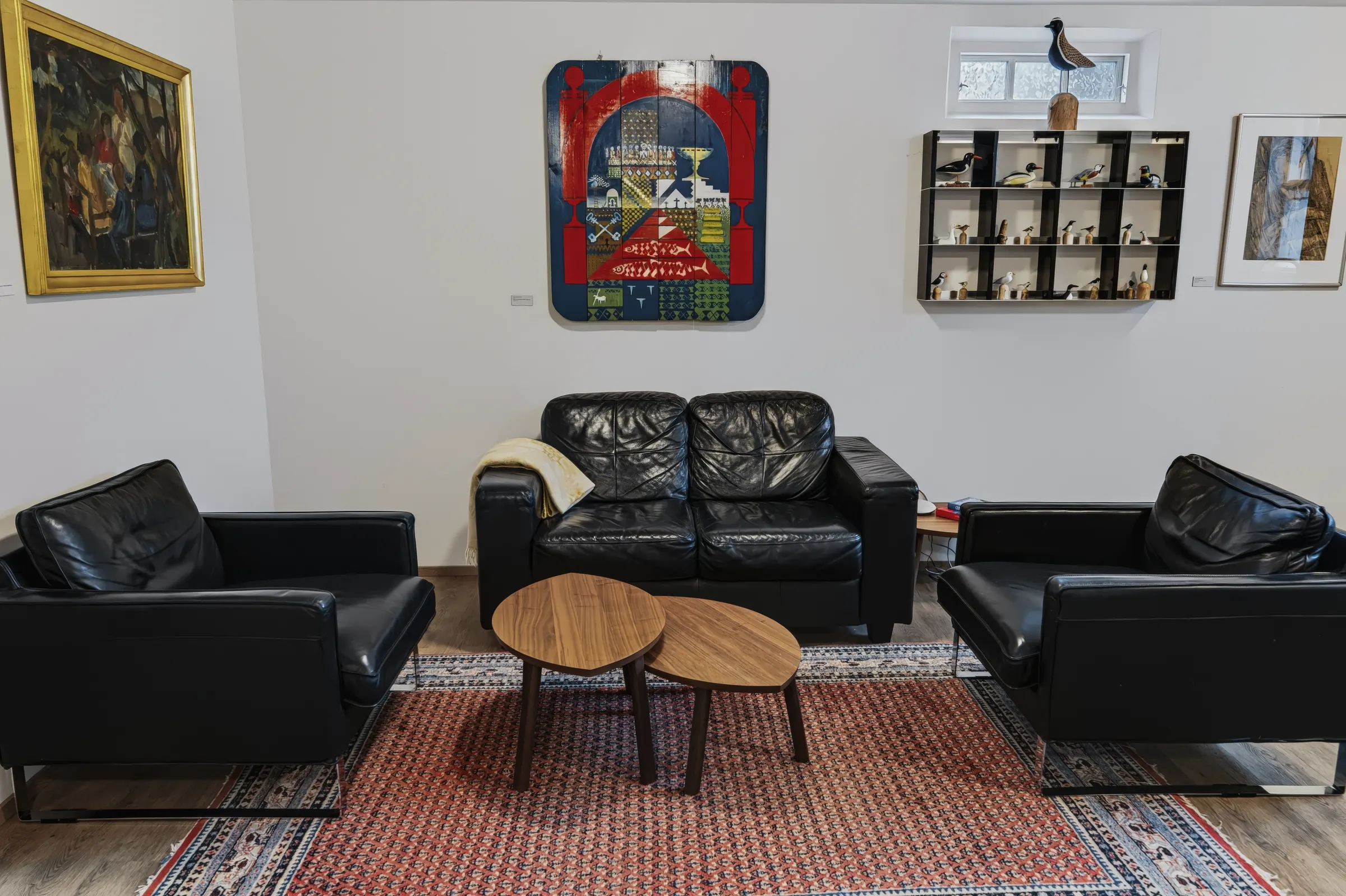 The living room of the Classic Apartment, with black leather sofas under a bright painting