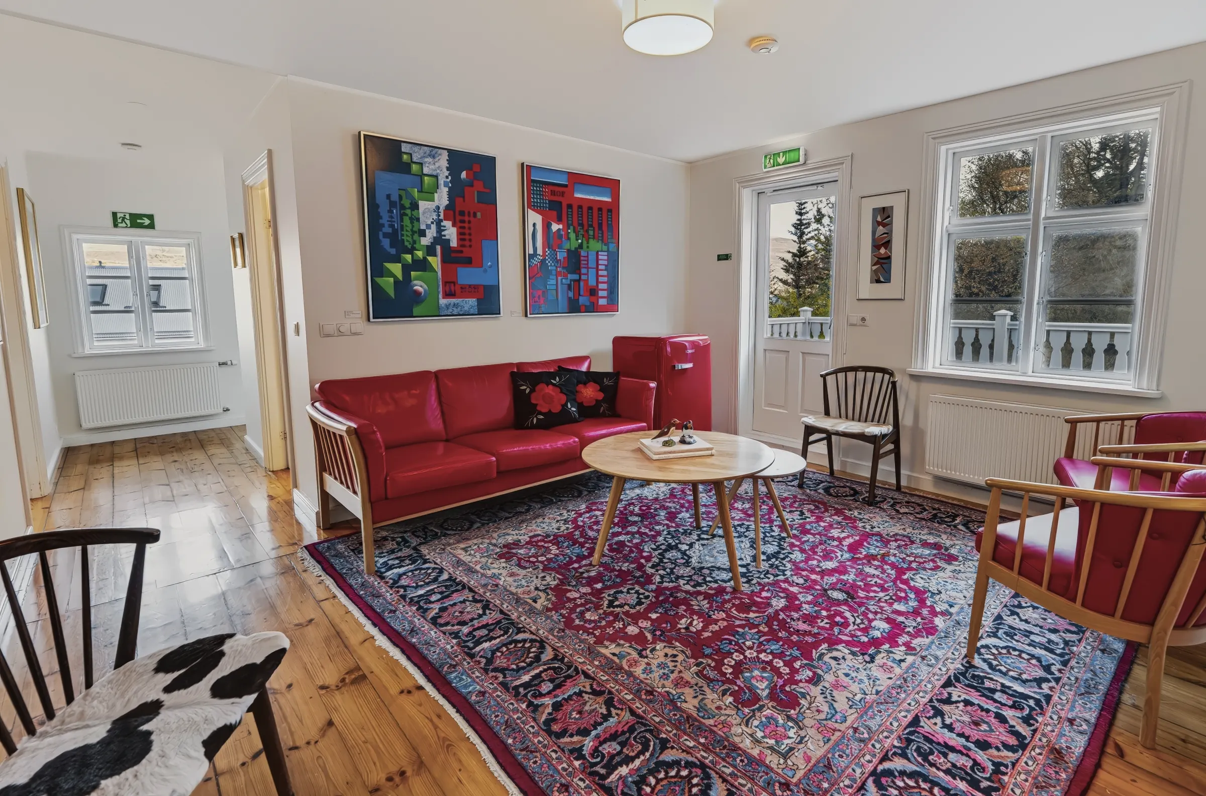 The upstairs sitting area of the Grand Residence: a red sofa under two paintings, a patterned carpet and the door to the terrace