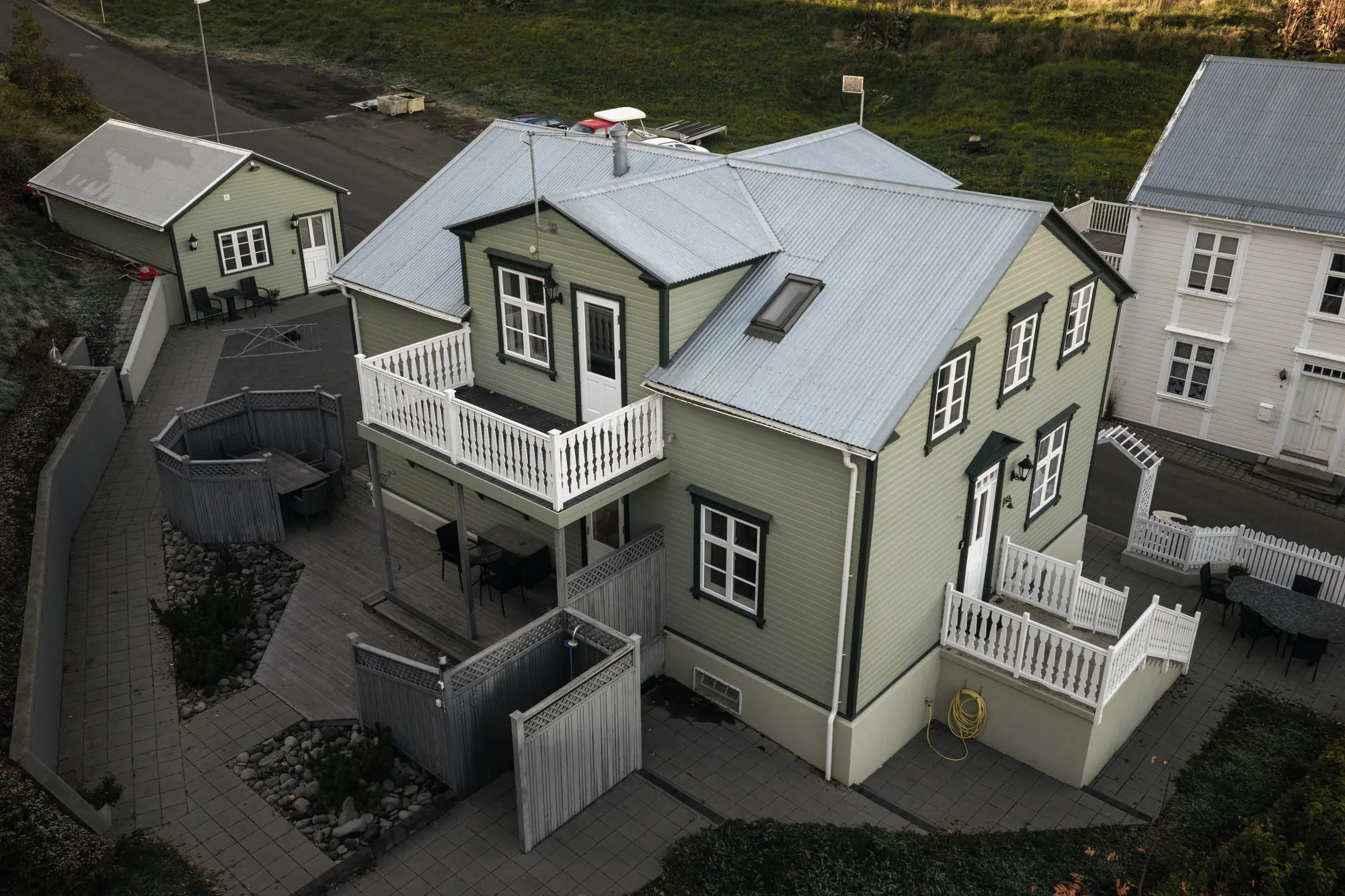 The house from above, with the garden terrace and its seating, the white balcony and the entrance stairs