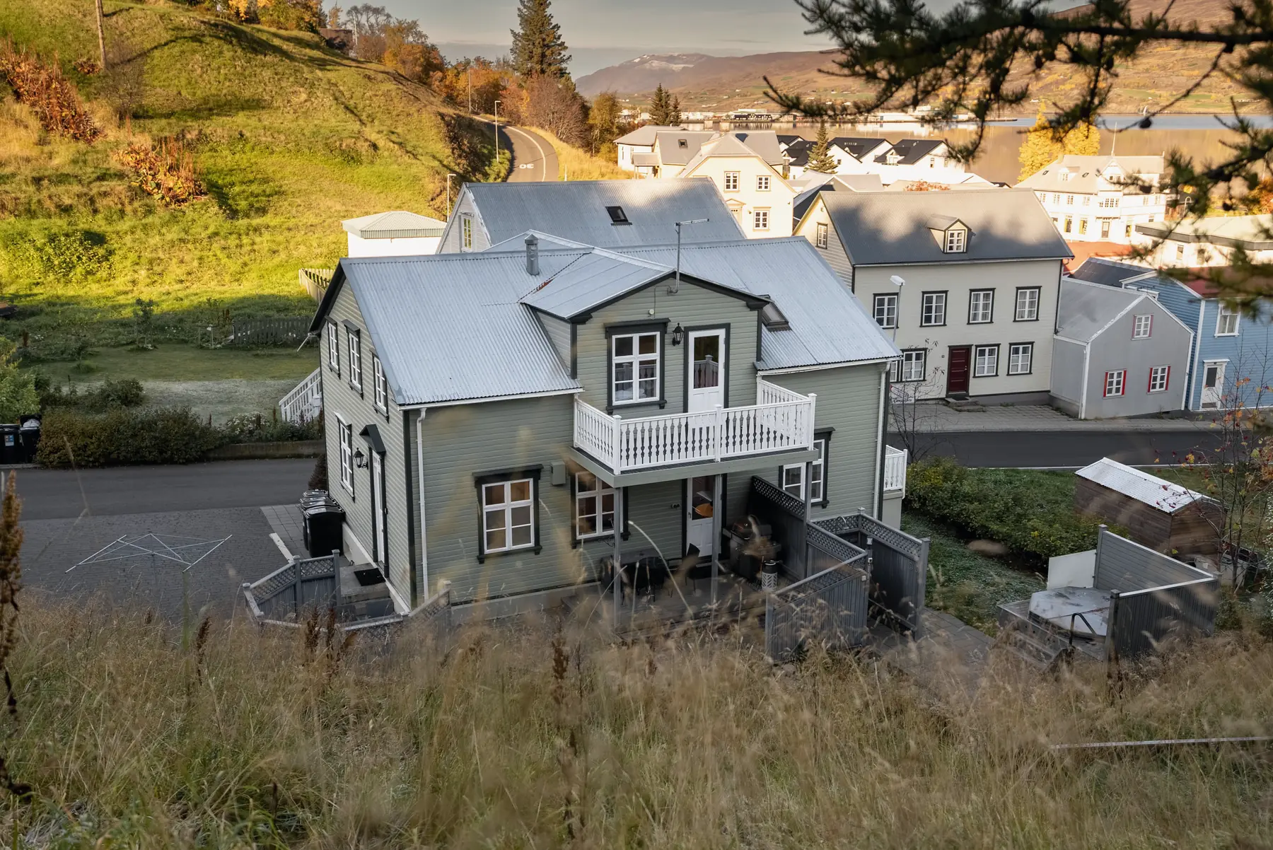 The house among the roofs of the old town, seen from the hillside in the evening sun, with the town beyond