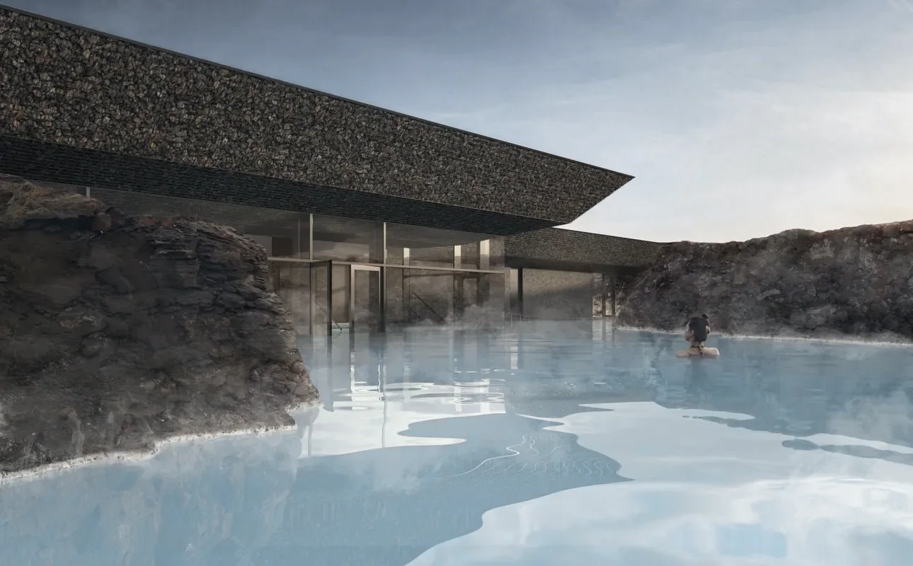 A pale blue geothermal lagoon beside a low stone building with a turf roof